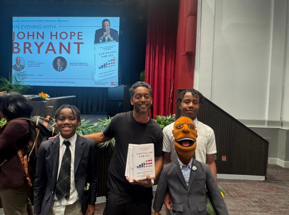 MBV youth presenting the Financial Ed puppet to John Hope Bryant at the Capitalism for All book launch